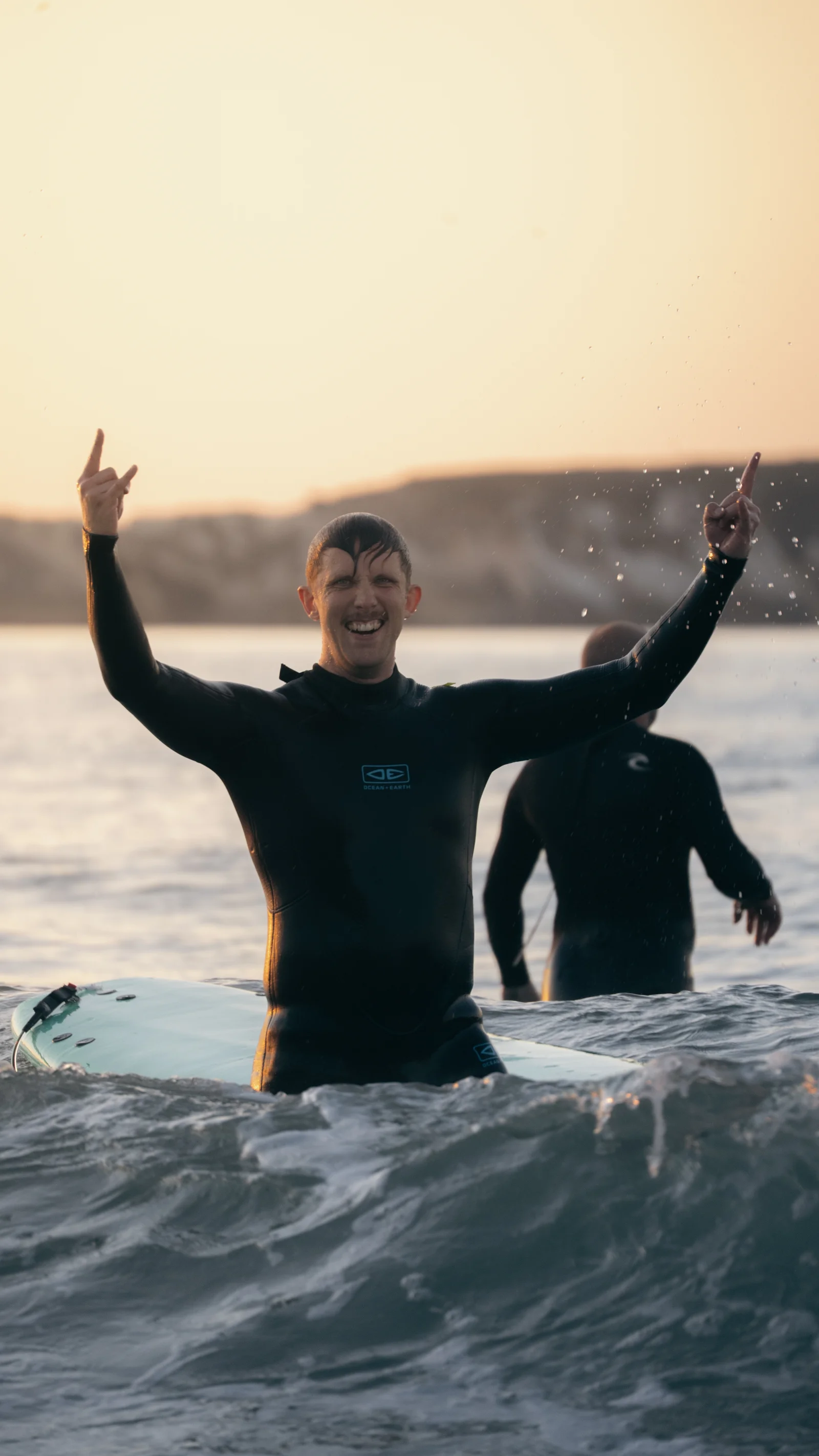 Surfer celebrating in the waves at sunset