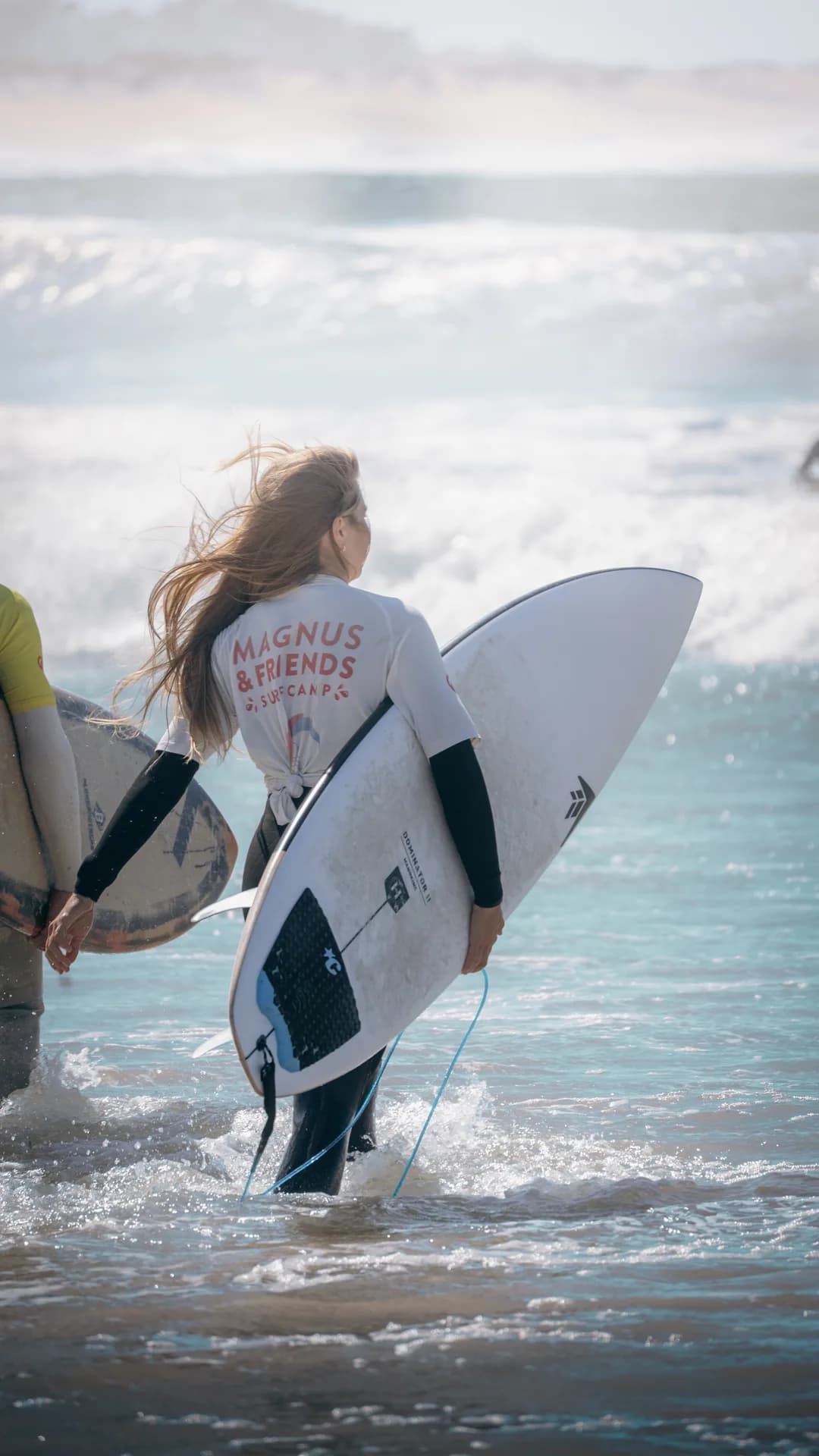 Surfer walking into the waves with board